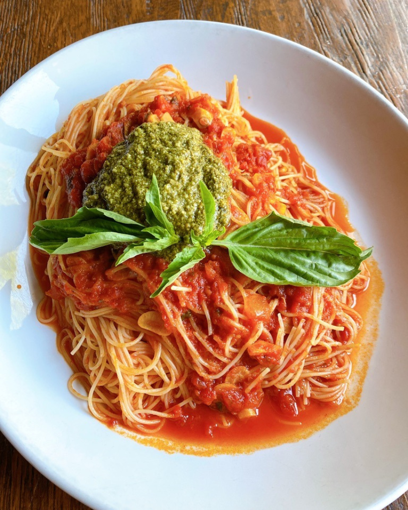 Plate of spaghetti pasta topped with rich red marinara sauce and sprinkled with fresh herbs